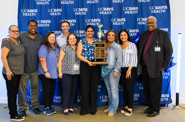 Group of employees pose with trophy