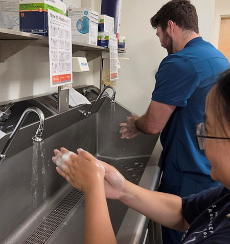 Residents rotate through interactive learning stations focused on hand hygiene, glove use, and infection prevention practices.