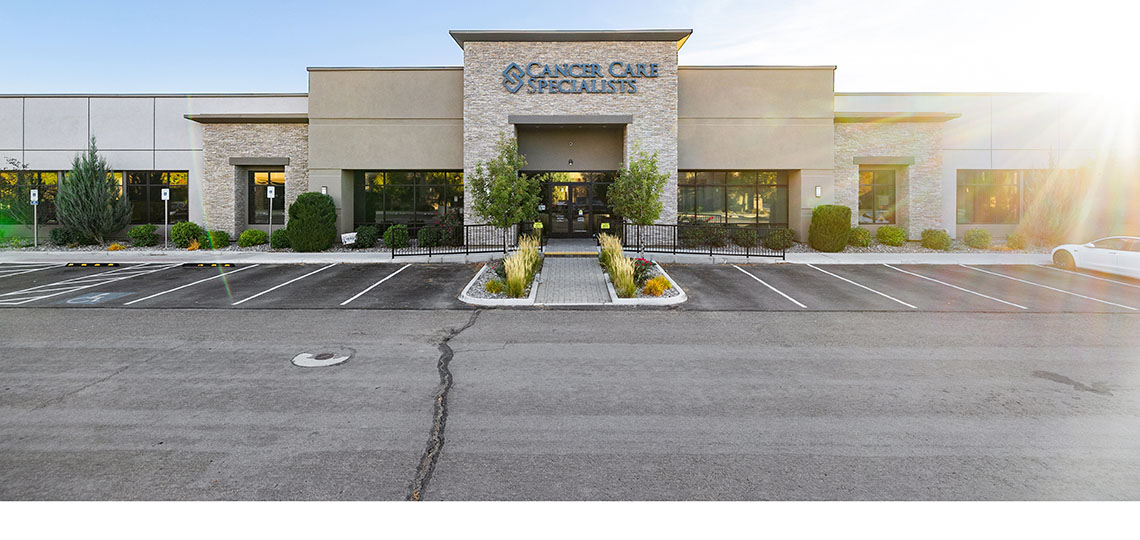 The view from the parking lot of a large tan and stone building, with the name Cancer Care Specialists over the entrance
