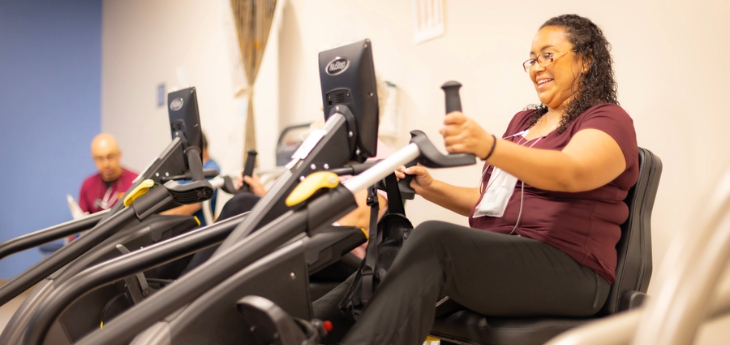 A patient exercises on a seated cardio machine during a cardiac rehabilitation session.