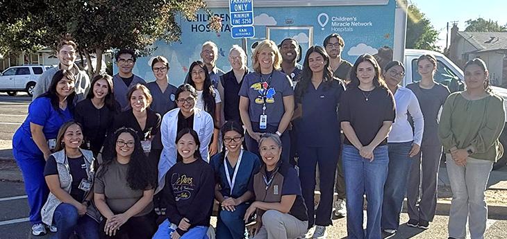 Group of people stand in front of pediatric mobile clinic van