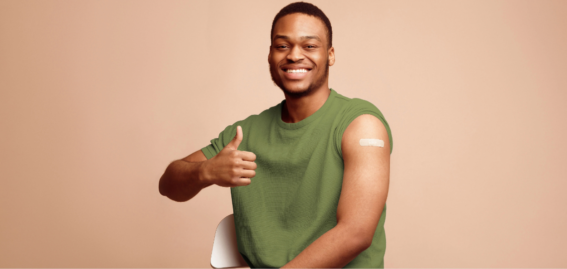 A smiling man gives a thumbs-up after receiving a vaccination.