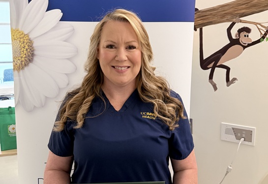Shellyn Brown, MSN, RN, CPHON, in Pediatric Infusion, stand in front of a DAISY banner. 