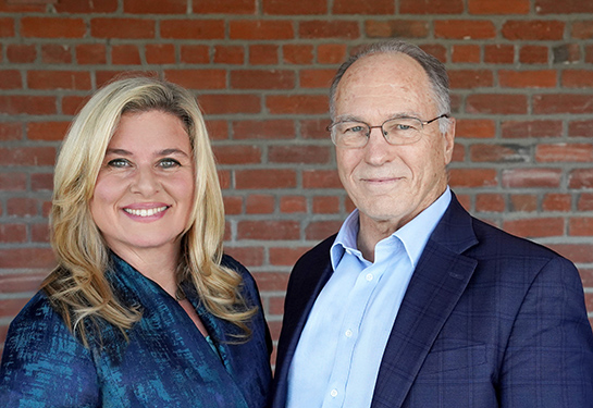 Professors Charles DeCarli (right) and Rachel Whitmer (left) are standing together and smiling to the camera.