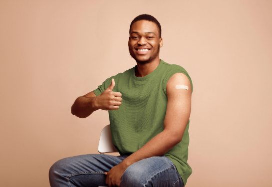 A smiling man gives a thumbs-up after receiving a vaccination.