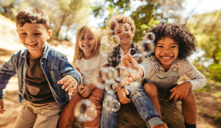 four kids playing with bubbles