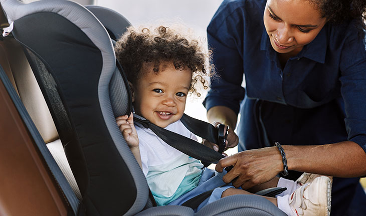 mom buckling her child in a car seat