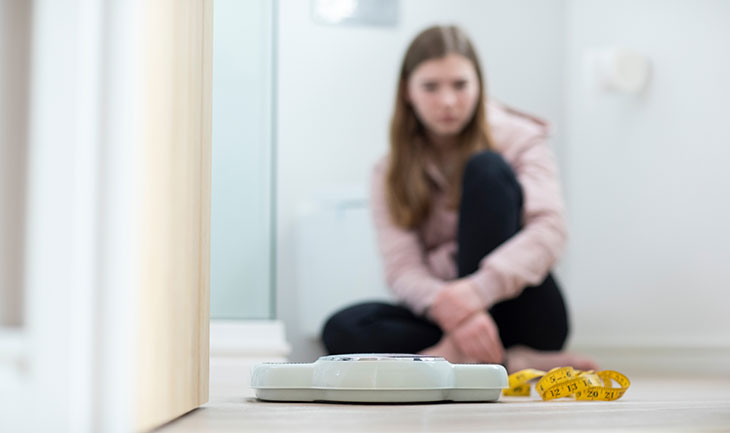 girl sitting on the floor looking at a scale