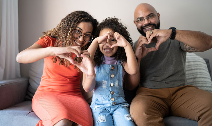 family making heart shapes with their hands