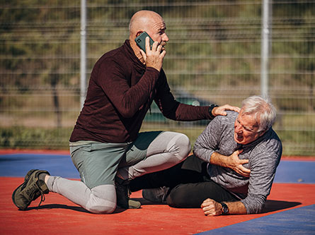 one man on the phone while a second man holds his chest
