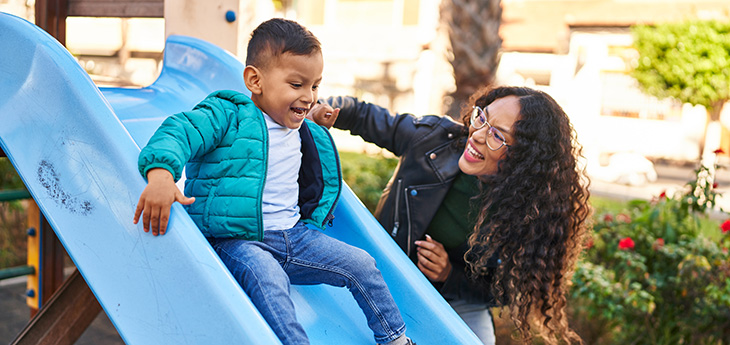Mother and son playing on slide at park
