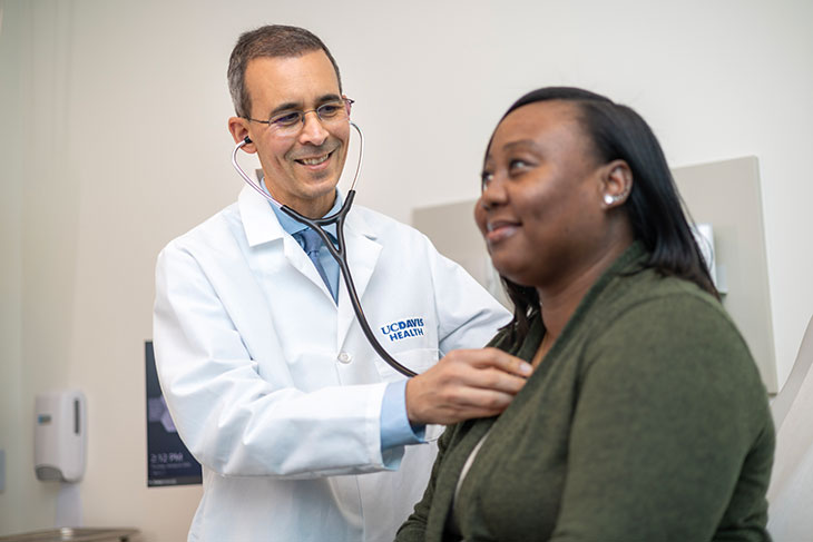 male doctor listening to a female patient's heart with a stethoscope at the Folsom clinic