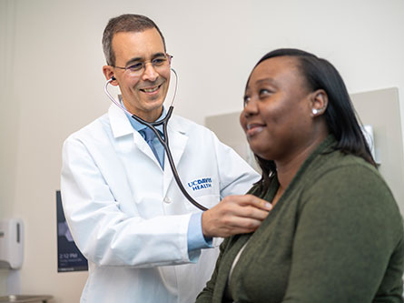 male doctor listening to a female patient's heart with a stethoscope at the Folsom clinic
