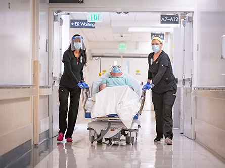 nurses wheeling in patient on hospital bed