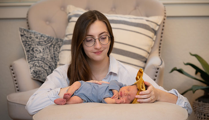 mom looking down with her arms around her infant who is laying down