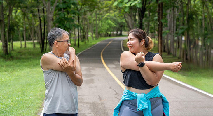 Older man and younger woman stretching before going on walk/run on a trail