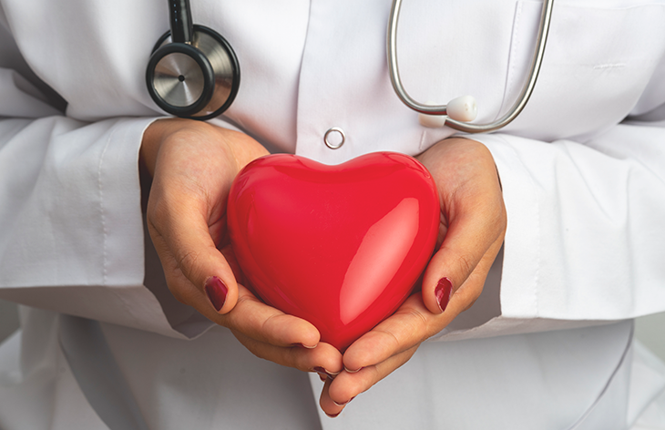 health professional holding a plastic heart shape in her hands with stethoscope around her neck