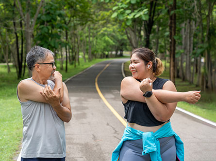 Older man and younger woman stretching before going on walk/run on a trail