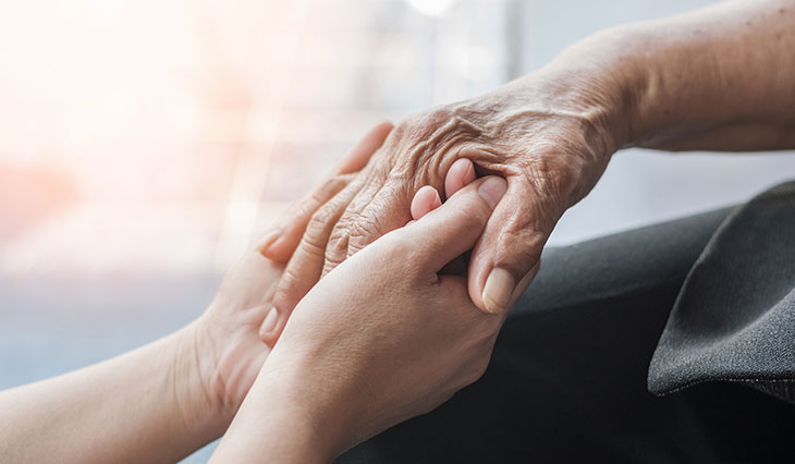 Person's hand holding an older person's hand