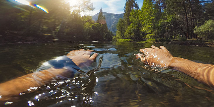 person swimming in a river with trees around, water safety in rivers and lakes