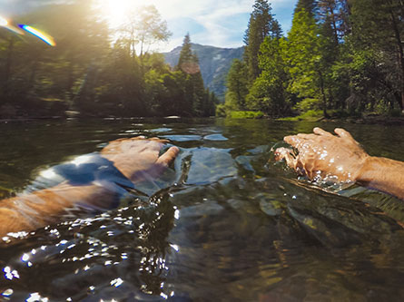 person swimming in a river with trees around, water safety tips in rivers and lakes