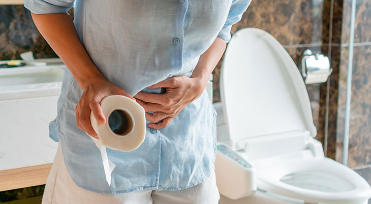 woman holding a roll of toilet paper in the bathroom having diarrhea or constipation