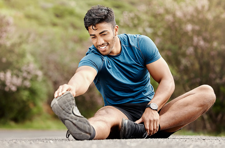 man sitting stretching outside to get the benefits of stretching and flexibility