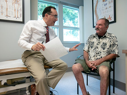 orthopaedic surgeon discussing knee replacement with a male patient in a clinic