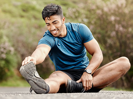 man sitting stretching outside to get the benefits of stretching and flexibility