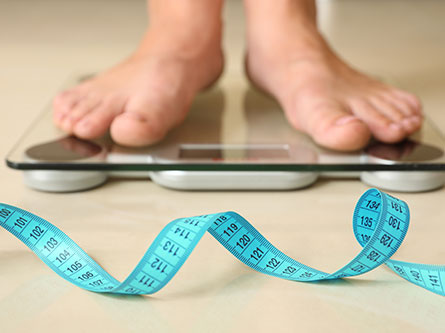 person standing on a scale looking for weight loss tips