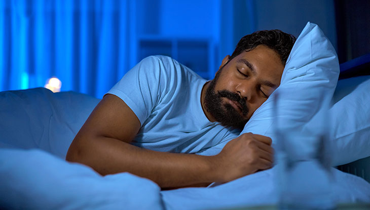 man sleeping in bed after taking melatonin and learning the side effects