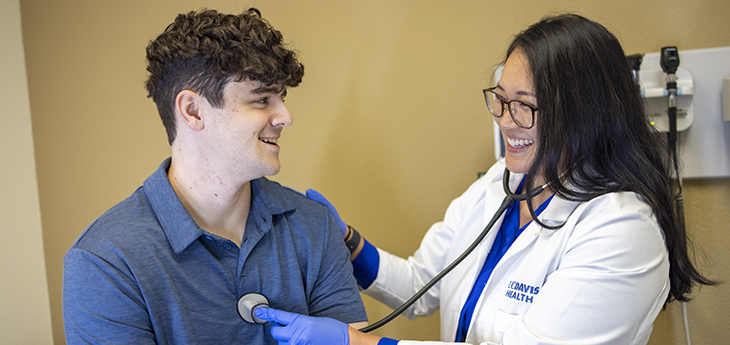 Doctor performing a routine examination on a young adult patient using a stethoscope.