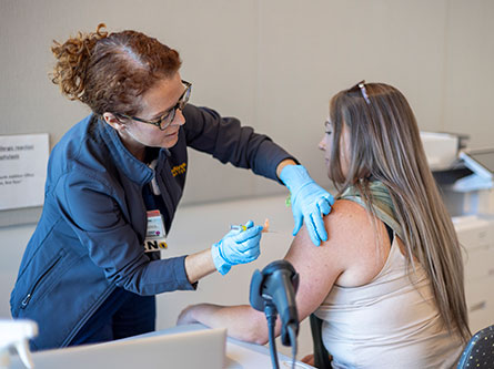 Nurse giving woman a covid and flu shot for symptoms
