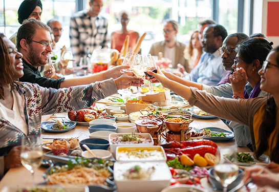 Group of people enjoying a meal together, clinking glasses while sitting at a table