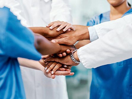 Diverse group of healthcare providers’ hands stacked together.