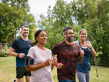 four people running together in a park