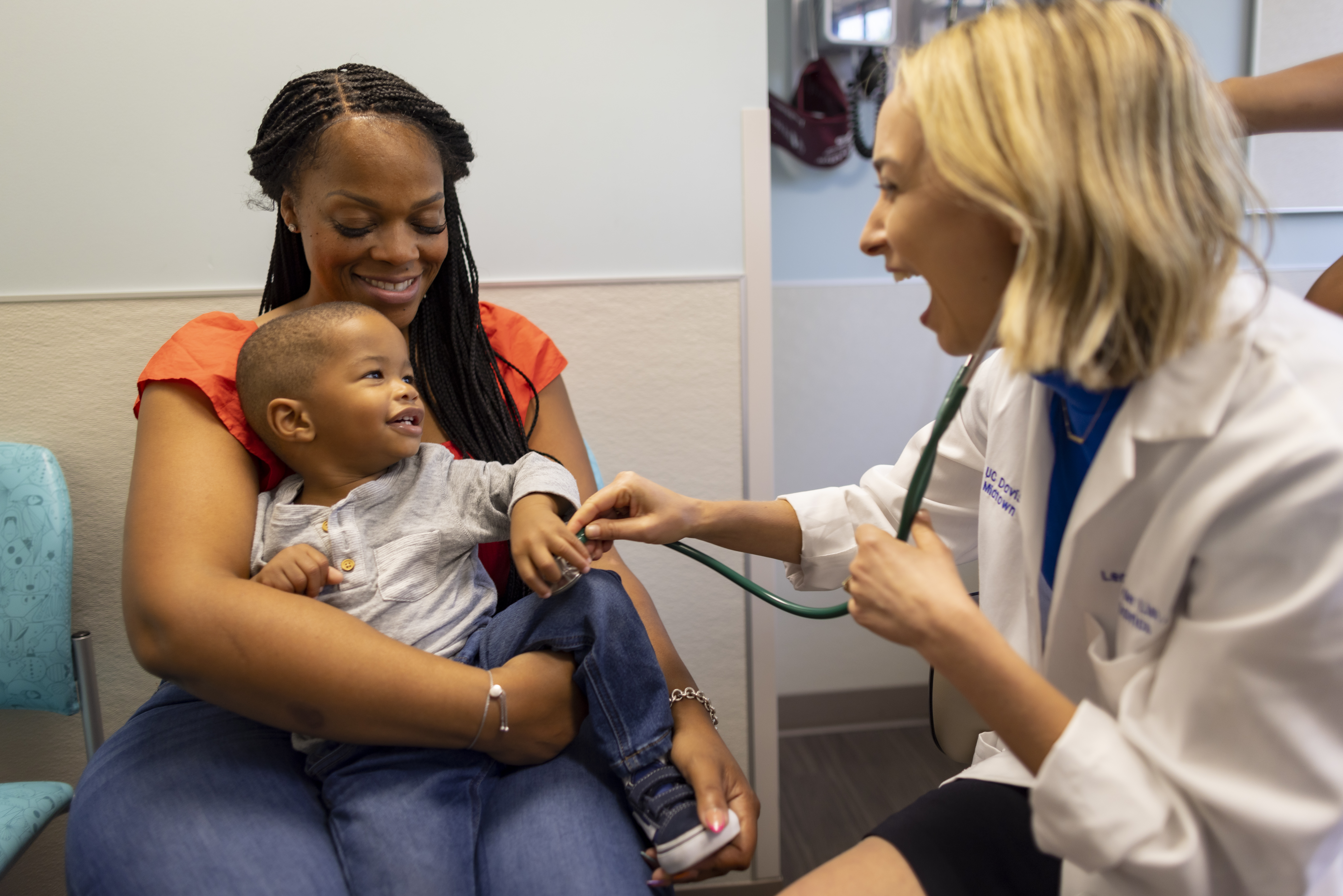 A pediatric patient and their mother smile at a pediatric primary care provider.