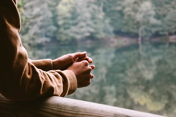 person standing with hands clasped 