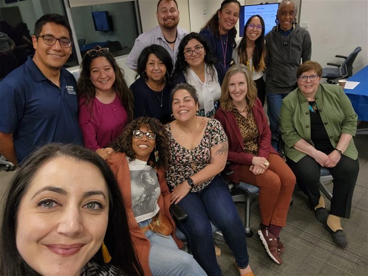 thirteen people standing and sitting in a classroom