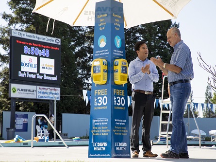 two people at a sunscreen kiosk talking