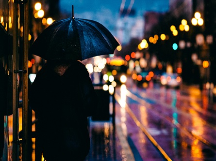 person standing in the rain at night with an umbrella