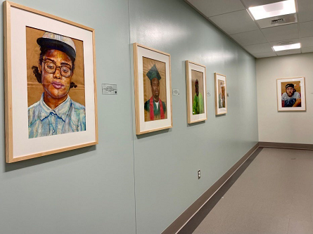 A hallway with painted portraits by artist Beth Consetta Rubel