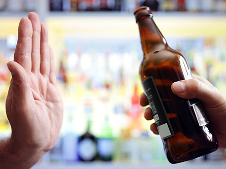 Hand held up to say 'no' to offered beer bottle