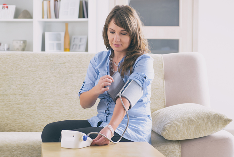 woman taking her blood pressure on her couch