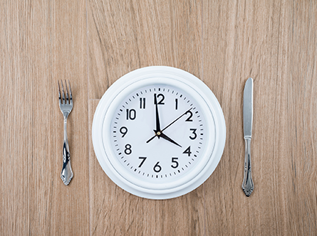 clock on table next to fork and knife