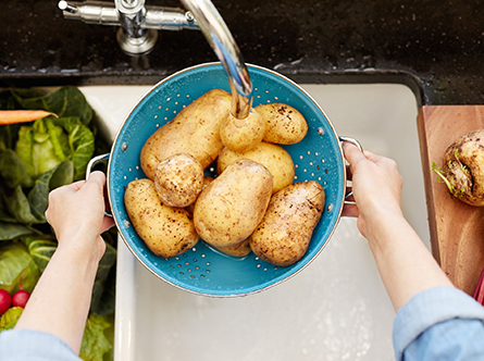 potatoes being washed in a sink