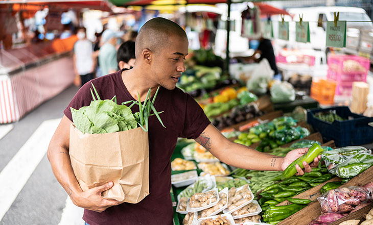 man picking out produce at farmers market