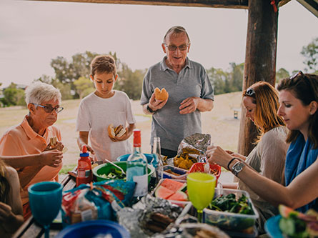 family eating around a table at a park