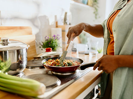 woman cooking vegetables in a pan on the stove
