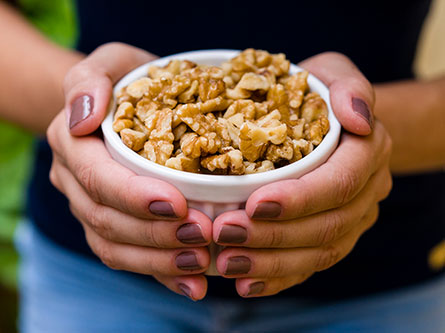 two hands holding a bowl of walnuts